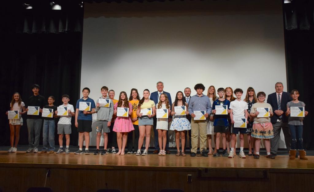 students standing on stage holding certificates